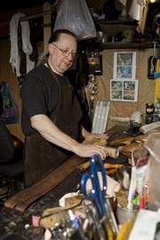 Leather crafter Chip Lorimer dyes a belt in his workshop.